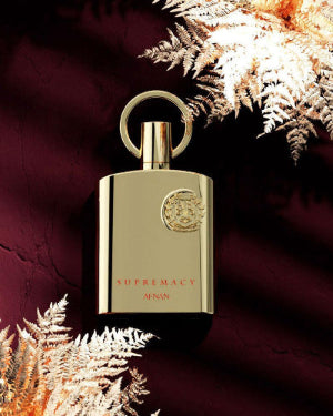 Afnan Supremacy Gold fragrance bottle on a dark background with fern accents.